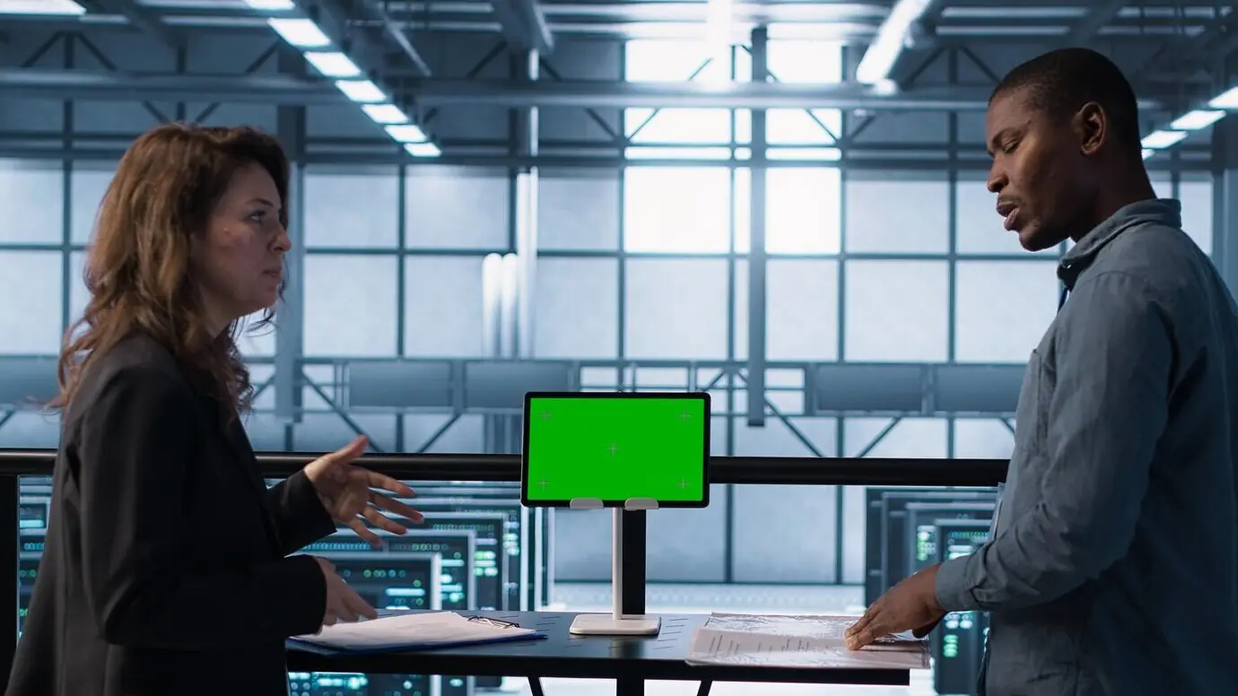 Rechenzentrumsteam nutzt ein Tablet mit Greenscreen-Mockup und prüft Unterlagen.